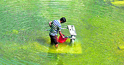 A man collects drinking water from a partially submerged handpump in Srinagar on Thursday