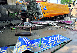 A damaged school bus in Srinagar (top); and a damaged wall of a government school in the Phalian Mandal area on the outskirts of Jammu