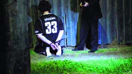 A man detained by the police during a raid kneels on the ground in Sydney, in this still image taken from police handout video on Thursday.