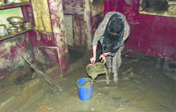 A woman cleans her house covered with slush after the floodwater receded in Srinagar on Friday. Tribune Photo: Yawar Kabli