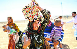 Syrian Kurds carry their belongings after crossing the border between Syria and Turkey near the southeastern town of Suruc on Saturday. AFP