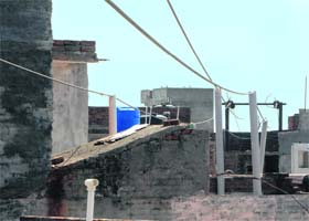 Residents have used bamboo sticks and plastic pipes to raise the height of the high-tension wires passing over rooftops of their houses