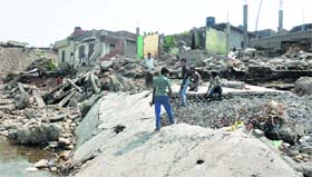Labourers break the concrete slab of a damaged house at the Belecharana area of Jammu.