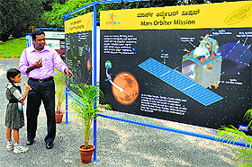 A man and his daughter look at a poster on Mars Mission at Nehru Planetarium in Bangalore on Tuesday.