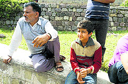 Kartar Singh along with his nephew Rakesh Singh waits for the bodies of his families members who are still buried under the debris