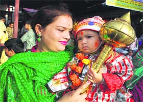 A mother holds her child dressed up as langoor
