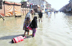 A woman along with her daughter drags an LPG cylinder through a flood-hit area in Srinagar on Thursday. Tribune Photo: Amin war