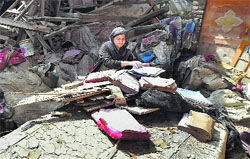 A woman salvages books from the rubble of her collapsed house as the floodwaters recede in Srinagar on Thursday. PTI