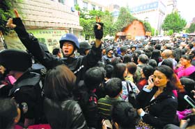 Tragedy in China: A police officer tries to maintain order outside a school after a stampede at a primary school in Kunming on Friday