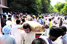 Farmers carry seed bags from the kisan mela organised by the PAU regional centre in Bathinda on Saturday.