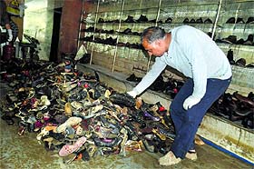 A shopkeeper takes out damaged shoes from his shop in Srinagar on Sunday.
