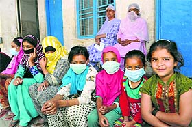 Children wearing masks wait outside a medical camp organised by the BSF on the outskirts of Srinagar on Sunday