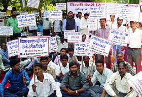 Owners of battery rickshaws sit on a dharna against the court order at Mandi House in New Delhi on Monday.