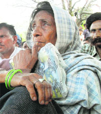 Dhani Devi (84) waits for the bodies of her family members as a JCB machine is brought to Saddal village in Udhampur district on Monday.