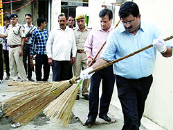 Delhi Police Joint Commissioner Sandeep Goel (R) launches a cleanliness drive in the Pahar Ganj area in New Delhi on Tuesday