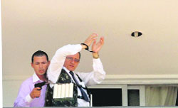 An unidentified man holding a gun parades a handcuffed hostage on the 13th floor balcony of the Saint Peter Hotel in Brasilia on Monday