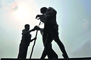 A man washes the statue of Mahatma Gandhi at the Satwari Chowk in Jammu on the eve of Gandhi Jayanti on Wednesday.