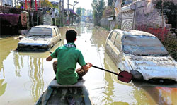 A youth rows a boat in a flooded street at Rajbagh in Srinagar on Wednesday. Several areas of city are still submerged. PTI