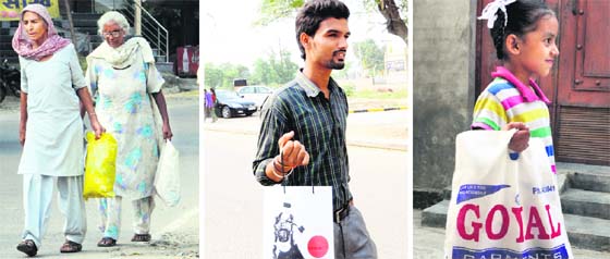 (From left) Two elderly women carry their belongings in polythene bags; a youth carries a bag made of cardboard; and a child with a cloth bag in Amritsar.