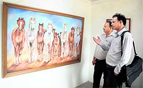 Visitors admire a painting during an exhibition organised by the Unique Society of Artists at Mani Majra on Sunday.
