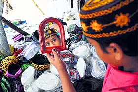 A boy selects a cap outside Khatikaan Talab Mosque;