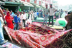 People buy carpets from a market on the eve of Eid-ul-Zuha in Srinagar on Sunday