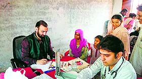 A doctor prescribes medicines to a patient at a camp at Gorkha Nagar Boys Middle School in Jammu on Sunday.