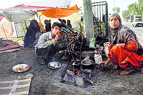 Members of a family displaced by the floods have tea near their tent on the outskirts of Srinagar. 