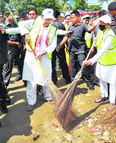 Assam Chief Minister Tarun Gogoi sweeps a road during the Clean Guwahati campaign on Sunday.