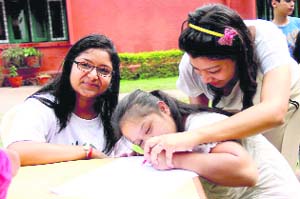 MAD volunteers help an inmate in drawing a sketch at Raphael Home in Dehradun on Sunday