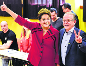 Brazils President and Workers Party candidate for re-election, Dilma Rousseff (L), gestures to photographers alongside her partys candidate for Governor of Rio Grande do Sul state, Tarso Genro, after Rousseff voted in the first round election in Port Alegre on Sunday.