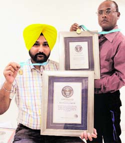Artists Harwinder Singh Gill >> and Jagmohan Kanojia display their medals and certificates awarded by the Guinness Book of World Record in Amritsar.