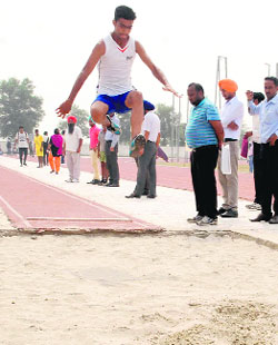 An athlete takes part in a long jump event during the district-level athletics tournament in Bathinda on Tuesday.