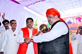 BJP candidate Pawan Beniwal offers a mace to party president Amit Shah in Ellenabad on Tuesday. 