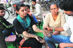 A woman gets henna applied on her hand ahead of Karva Chauth at Dhobi Bazaar in Bathinda on Thursday