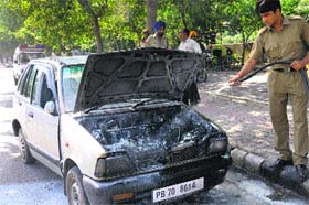 Freak mishap: A fireman pours water on a car that caught fire near the airport light point in Chandigarh on Thursday.