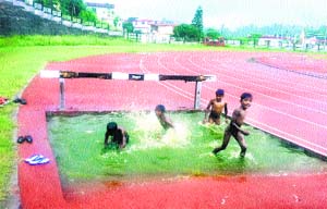 Children of migrant labourers play in the rainwater accumulated in a pond near the track in Hamirpur on Thursday