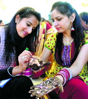 Women apply heena (mehndi) on their hands on the eve of Karva Chauth in Shimla on Friday.