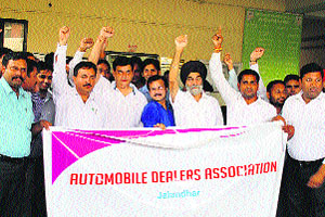 Members of the Automobile Dealers Association hold a protest in front of the office of the DTO against hike in the registration charges of vehicles in Jalandhar on Friday.