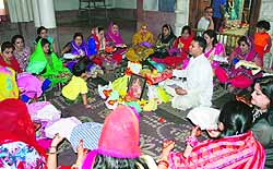 Married women exchange thalis during Karva Chauth pooja at a temple