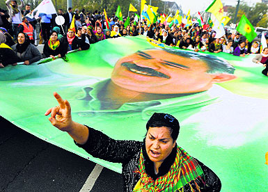 A woman gestures as she holds a large flag with the image of Abdullah Ocalan, jailed leader of the Kurdistan Workers Party (PKK), during a demonstration against Islamic State attacks on Kobani, in Duesseldorf (Germany) on Saturday. 