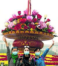 Tourists pose for photos with masks on Tiananmen Square during a hazy day in Beijing. 