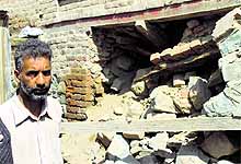 A man stands outside his house, which was damaged in the recent floods, in south Kashmir's Pulwama district on Sunday