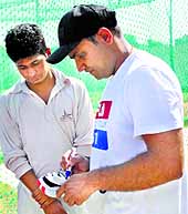 The cricketer signs his gloves before presenting them to Prince, who got his wicket in the nets