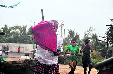 Fishermen run against the wind as trees were uprooted and power cables snapped after the a powerful cyclone slammed into the southern city of Visakhapatnam at Gopalpur, Odisha on Sunday