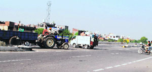 A tractor-trailer crosses a junction unmindful of the upcoming traffic on the outskirts of Amritsar on Monday.