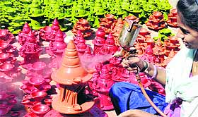 A girl gives the finishing touches to an earthen pot ahead of Diwali at Bhar Majra village in Mohali on Monday