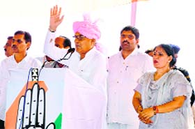 Chief Minister Bhupinder Hooda addresses a rally in Jhajjar on Monday, as Congress candidate Geeta Bhukkal looks on.