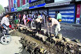 Municipal workers clean mud from drains at Lal Chowk in Srinagar. 