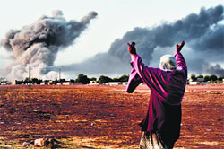 A woman reacts as smoke rises from the Syrian town of Kobani after an air strike on Monday. AFP